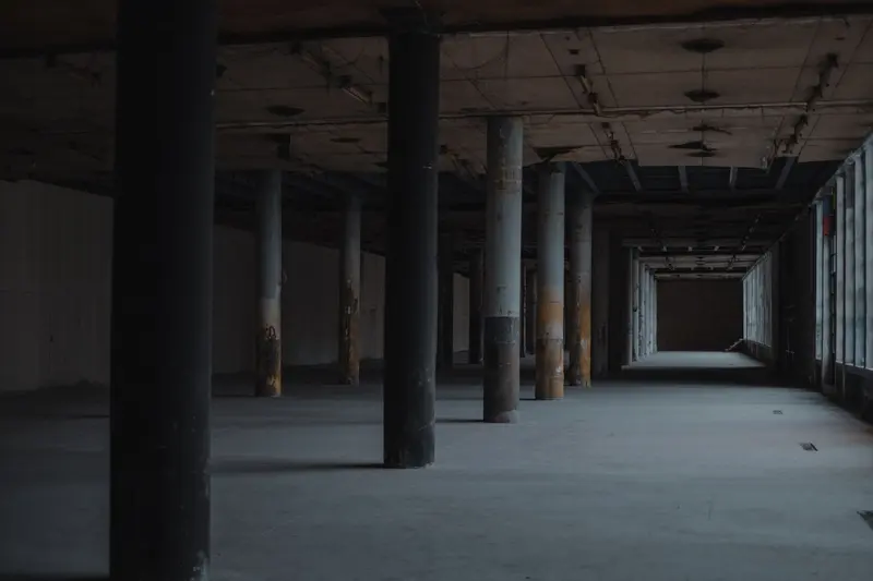 Verlassene Industriehalle mit Betonpfeilern und dunklem Durchgang — Stimmungsbild, keine Spielaufnahme